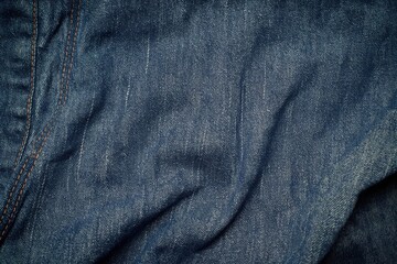 Poster - Blue jeans close-up view shows wrinkled denim fabric texture. Legs crossed at bottom and arms hanging down at top. Blurred background focuses on jeans natural texture.