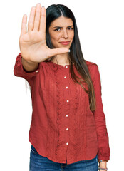 Young hispanic woman wearing casual clothes doing stop sing with palm of the hand. warning expression with negative and serious gesture on the face.