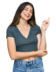 Poster - Young beautiful teen girl wearing casual crop top t shirt with a big smile on face, pointing with hand and finger to the side looking at the camera.