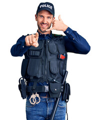 Canvas Print - Young handsome man wearing police uniform smiling doing talking on the telephone gesture and pointing to you. call me.