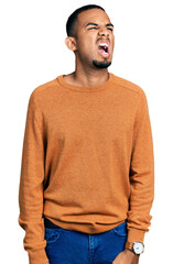 Poster - Young african american man wearing casual clothes angry and mad screaming frustrated and furious, shouting with anger. rage and aggressive concept.