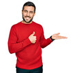 © Krakenimages.com - Young hispanic man wearing casual clothes showing palm hand and doing ok gesture with thumbs up, smiling happy and cheerful
