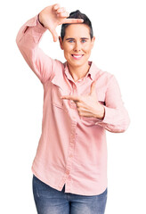 Young woman with short hair wearing casual clothes smiling making frame with hands and fingers with happy face. creativity and photography concept.