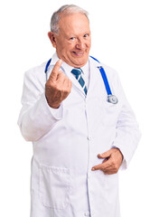 Wall Mural - Senior handsome grey-haired man wearing doctor coat and stethoscope beckoning come here gesture with hand inviting welcoming happy and smiling