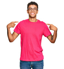 Wall Mural - Young handsome african american man wearing casual clothes looking confident with smile on face, pointing oneself with fingers proud and happy.