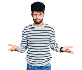 Canvas Print - Young arab man with beard wearing casual striped sweater clueless and confused with open arms, no idea concept.