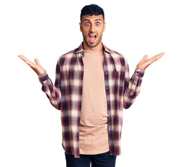 Wall Mural - Young hispanic man wearing casual clothes celebrating victory with happy smile and winner expression with raised hands