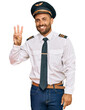 © Krakenimages.com - Handsome man with beard wearing airplane pilot uniform showing and pointing up with fingers number three while smiling confident and happy.