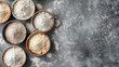 © AbstractAI - Variety of flour filled bowls on grey background top view Room for text