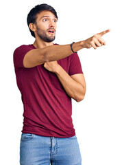 Canvas Print - Handsome hispanic man wearing casual clothes pointing with finger surprised ahead, open mouth amazed expression, something on the front