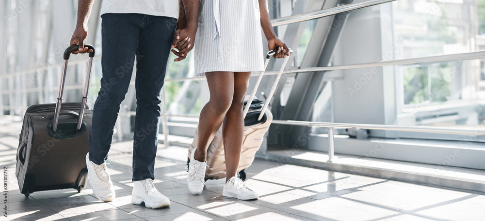 Black couple, a man and a woman, walk side-by-side through an airport ...