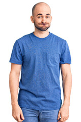 Canvas Print - Young handsome man wearing casual t shirt puffing cheeks with funny face. mouth inflated with air, crazy expression.