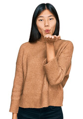 Wall Mural - Beautiful young asian woman wearing casual winter sweater looking at the camera blowing a kiss with hand on air being lovely and sexy. love expression.