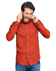 Poster - Young hispanic man wearing casual clothes covering ears with fingers with annoyed expression for the noise of loud music. deaf concept.