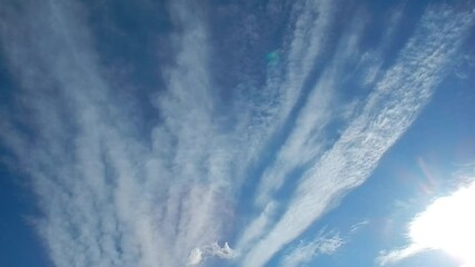 Poster - Blue sky, white clouds in the shape of rays slowly moving and sunlight - natural sunny calm background. Topics: abstraction, pattern, weather, meteorology, sky space, delicate clouds, atmosphere