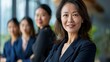 © PixelAI - Happy, smiling, confident middle-aged Asian businesswoman in a navy blue suit, leading her team with grace