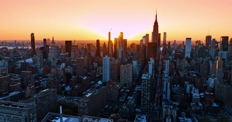 Wall Mural - Bright setting sun behind the skyline of gorgeous New York. Numerous cars move by the streets of vibrant city at sunset. Top view.