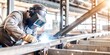 © hobonski - A skilled welder wearing protective gear is carefully welding metal in an industrial workshop setting, with sparks flying from the welding process.