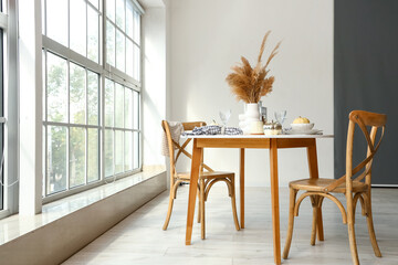 Poster - Autumn table setting with pampas grass and pumpkins in light kitchen near big window