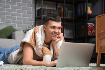 Canvas Print - Male author using laptop on floor at home