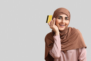 Sticker - Happy Muslim woman with credit card on grey background