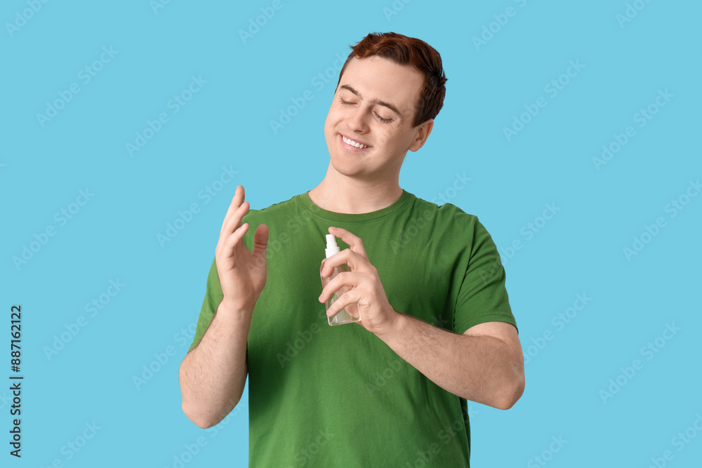 Young man with sanitizer on blue background