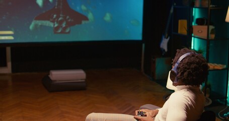 African american gamer plays game with spaceship shooting laser streams using crosshair overlay to hit targets. Ray tracing graphics and high FPS scifi videogame displayed on TV screen, dolly in shot