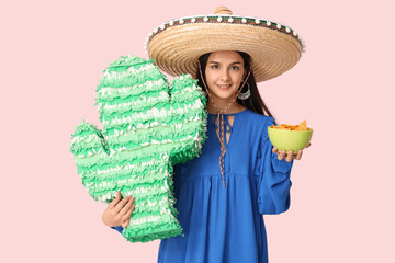 Sticker - Beautiful young woman in sombrero hat with pinata in shape of cactus and tasty nachos on pink background