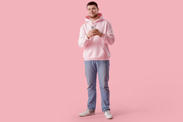 Canvas Print - Young bearded man using mobile phone on pink background