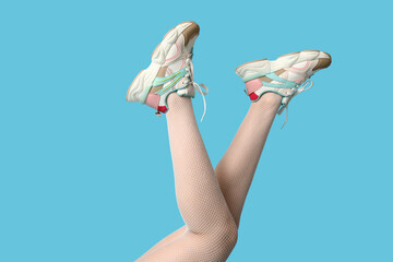 Wall Mural - Legs of young woman in sports shoes on blue background