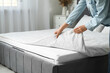 © Pixel-Shot - Woman with soft orthopedic mattress making bed at home, closeup