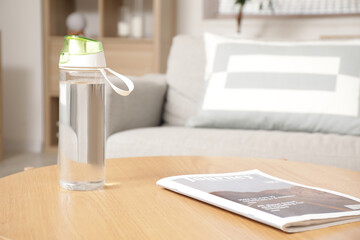 Canvas Print - Sports water bottle and magazine on table in living room, closeup