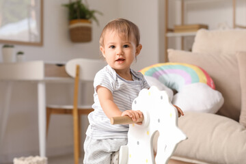 Wall Mural - Cute little happy baby with rocking horse at home