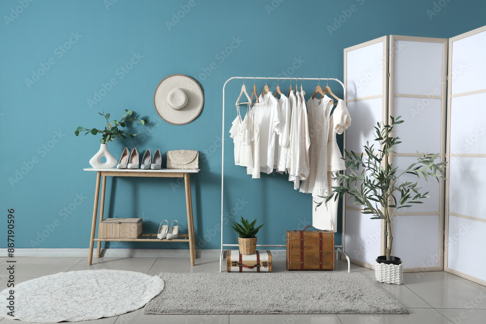 Rack with white clothes near blue wall in room