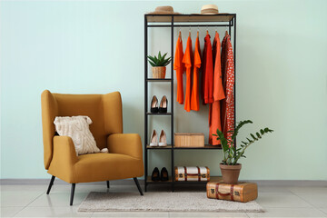 Wall Mural - Rack with orange clothes near white wall in room