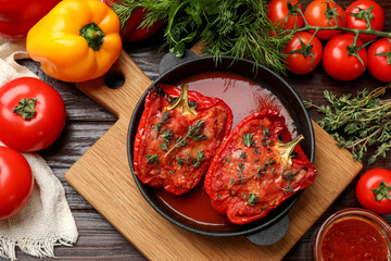 Wall Mural - Tasty stuffed peppers in dish and ingredients on wooden table, flat lay