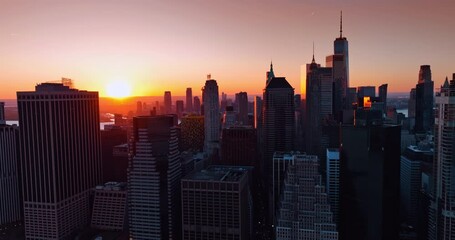 Wall Mural - Flight near the tops of the buildings of Manhattan. Tops of the highest buildings are lit with setting sun.