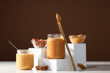 Wall Mural - Peanut paste in a glass jar with a table knife, on a light background.