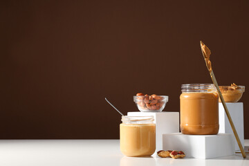 Wall Mural - Peanut paste in a glass jar with a table knife, on a light background.