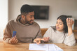 © Iryna - Couple Discussing Finances While Holding  Coin At Home