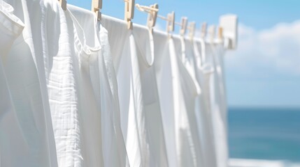 Sticker - White Clothes Drying on a Clothesline with a Blue Sky and Ocean Background.