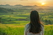 © Emanuel - Asian woman overlooking green fields at sunset