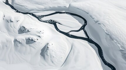 Aerial view of a snowy landscape with a river cutting through the pristine white snow