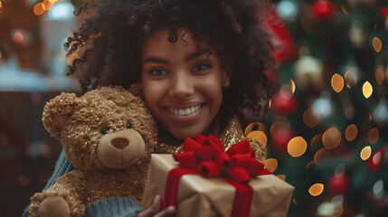 Joyful girl with curly hair holding a gift and teddy bear Christmas happiness concept 