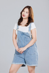 Wall Mural - Portrait of Asian cute cheerful young girl wearing denim overalls, stylish model woman with happy and cool sweet smile standing posing isolated on white background, Teenage and youth fashion.