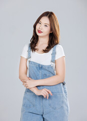 Wall Mural - Portrait of Asian cute cheerful young girl wearing denim overalls, stylish model woman with happy and cool sweet smile standing posing isolated on white background, Teenage and youth fashion.