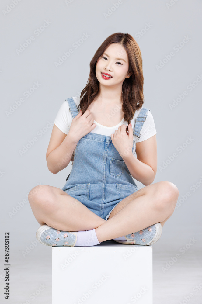 ortrait of Asian cute cheerful young girl wearing denim overalls ...