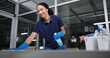© CineLens2024/peopleimages.com - Cleaner, cleaning table woman in office from dust, spray disinfect and protection from disease risk in building. Maintenance, person and chemical liquid for pest control, health and hygiene safety
