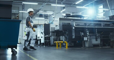 Leinwandbilder - Hispanic Female Worker in a Reflective Vest Walks Through a Modern Factory, Inspecting Equipment and Recording Data on a Tablet Computer. Employees Working at the Facility with Advanced Machinery
