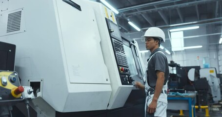 Leinwandbilder - Machinery Technician Closing the Lid and Programming a CNC Machine at an Advanced Metal Production Facility. Young Asian Man in Work Gear Setting Up the Manufacturing Process in a Factory